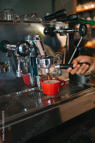 Making fresh espresso or cappuccino coffee in a coffee machine lathering and frothing the milk with hot steam, with the hands of a barista  © ArinaEmelyanova