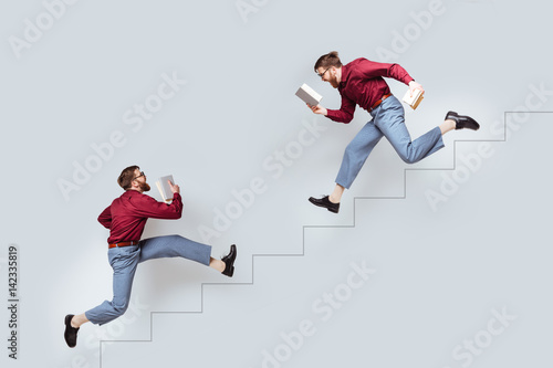 Two funny twin men with books running up and down photo