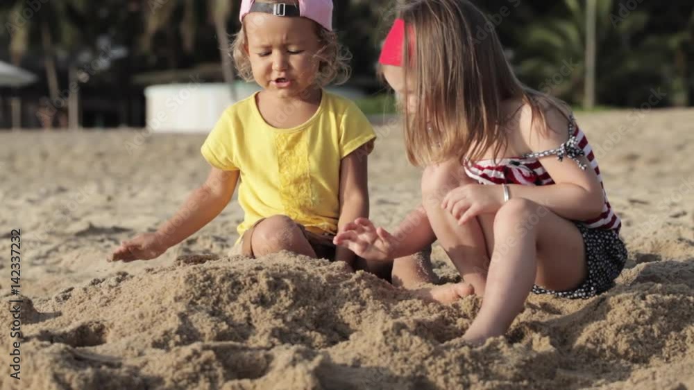 Two little cute girls playing with sand on the beach Two little cute girls playing with sand on the beach