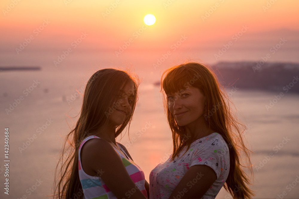 Mother and daughter at sunset. Sunset on the island of Santorini. Girl tourist on a background of the sea and the setting sun. Mother and daughter travel, Mother's love, Girl teenager and her mom.
Mother and daughter at sunset. Sunset on the island of Santorini. Girl tourist on a background of the sea and the setting sun. Mother and daughter travel, Mother's love, Girl teenager and her mom.