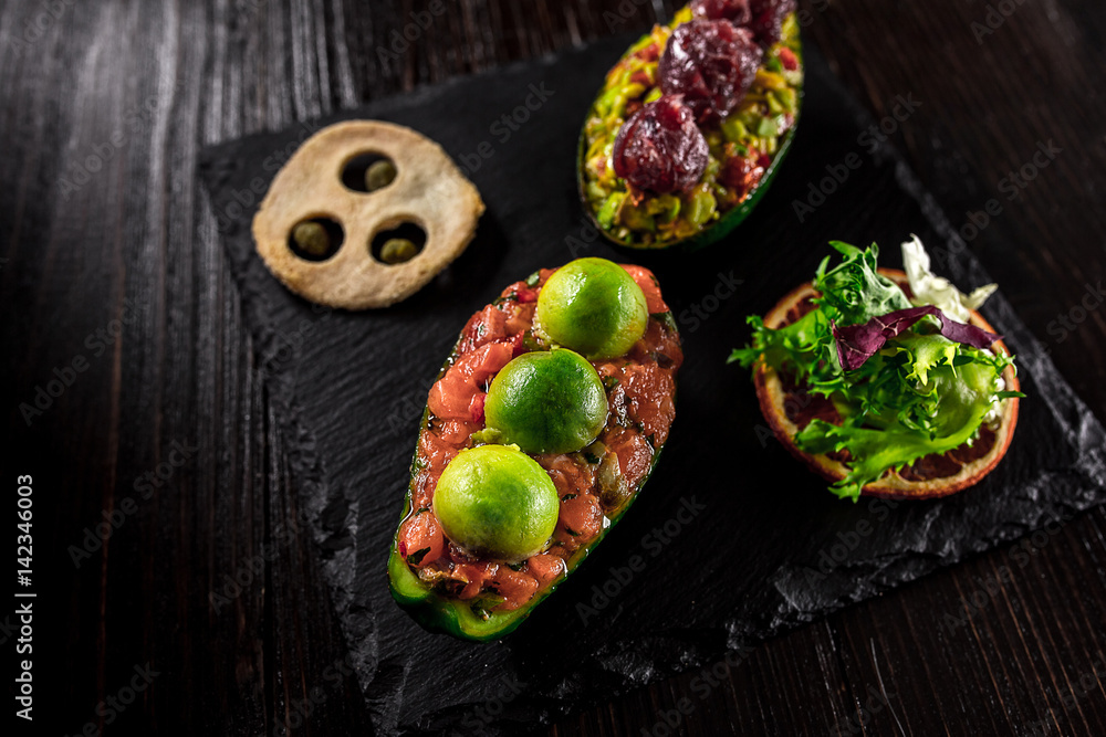Salmon tartare and avocado salad on a black background Salmon tartare and avocado salad on a black background