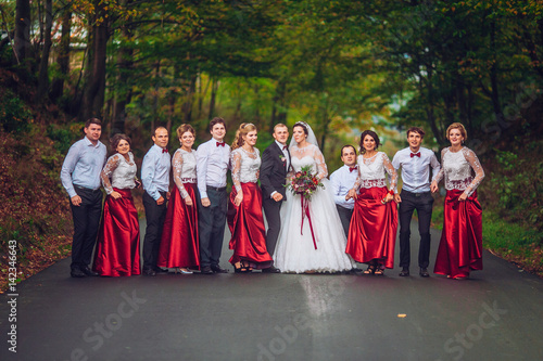 The bride and groom, newlyweds with bridesmaid and best man jump and having fun on road. Running funny people.