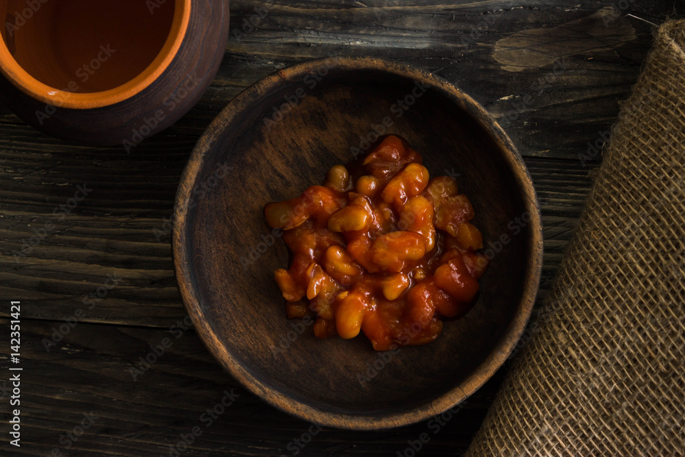 Beans in tomato in a wooden bowl. A delicious dish. Beans in tomato in a wooden bowl. A delicious dish.