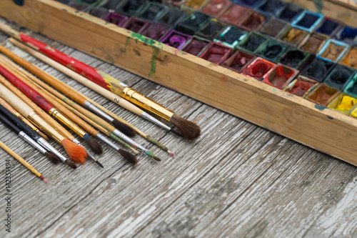 Box with watercolors and brushes on a wooden surface photo