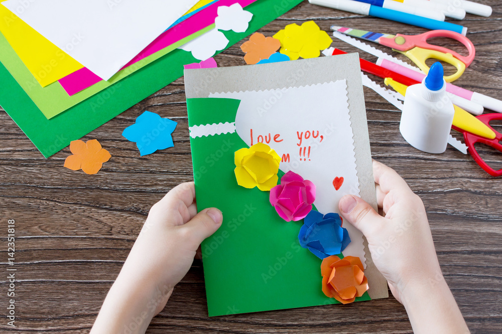 A child is holding a greeting card with flowers on Mother's Day ...