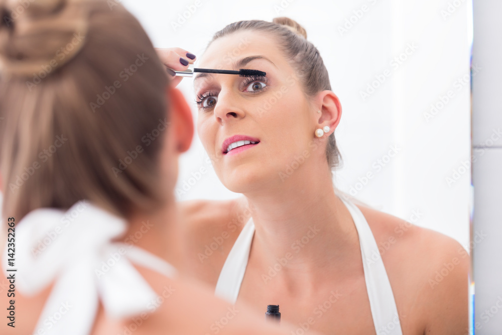 Woman using mascara on her eyelashes Woman using mascara on her eyelashes