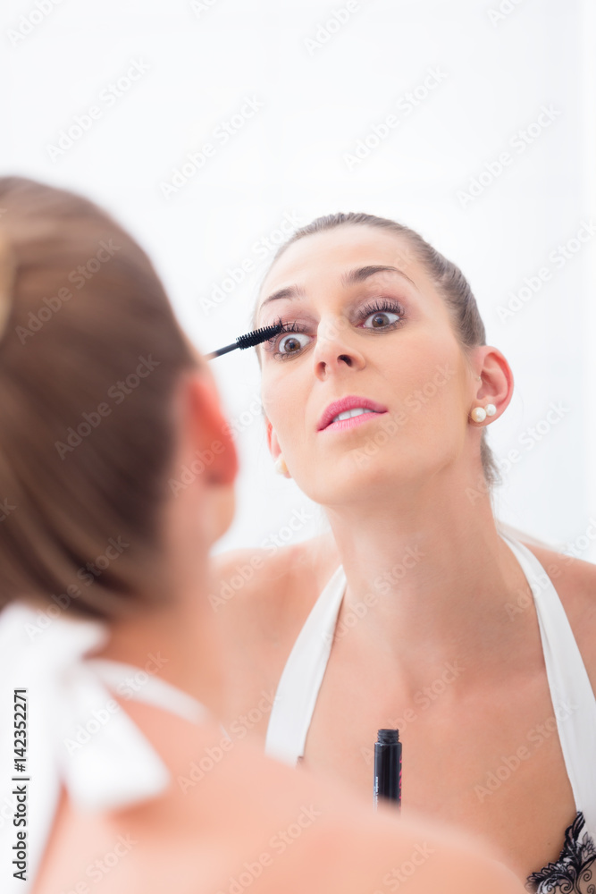 Woman using mascara on her eyelashes Woman using mascara on her eyelashes