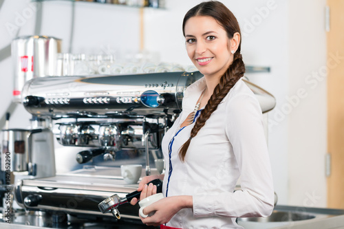Фотография Portrait of young waitress smiling near the coffee machine