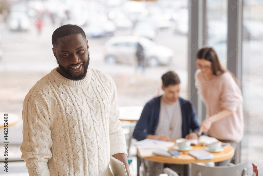 Young smiling man working with colleagues in a cafe Young smiling man working with colleagues in a cafe