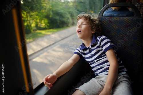 The little boy has fallen asleep in the bus.
