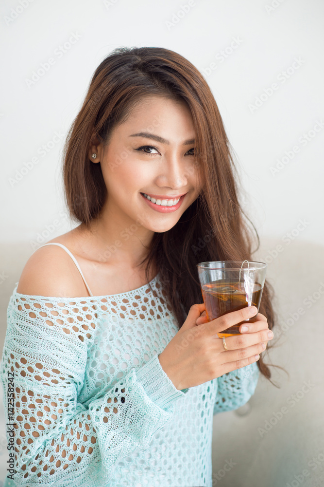 Beautiful young asian woman drinking her morning tea over a breakfast at home. Beautiful young asian woman drinking her morning tea over a breakfast at home.