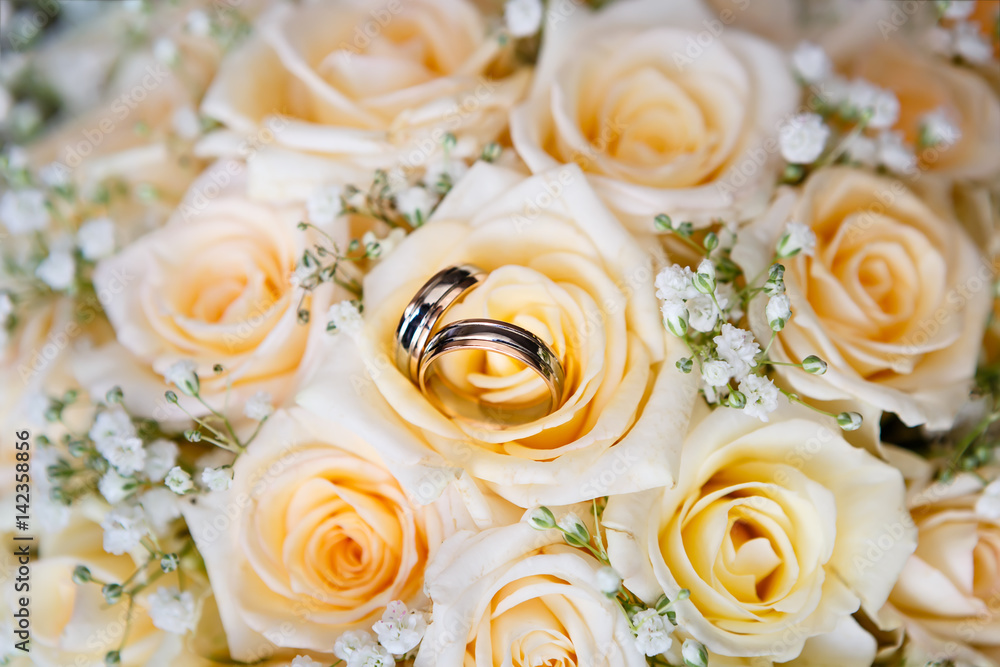 wedding rings on the roses. Wedding symbols, attributes. Holiday, celebration. Macro wedding rings on the roses. Wedding symbols, attributes. Holiday, celebration. Macro