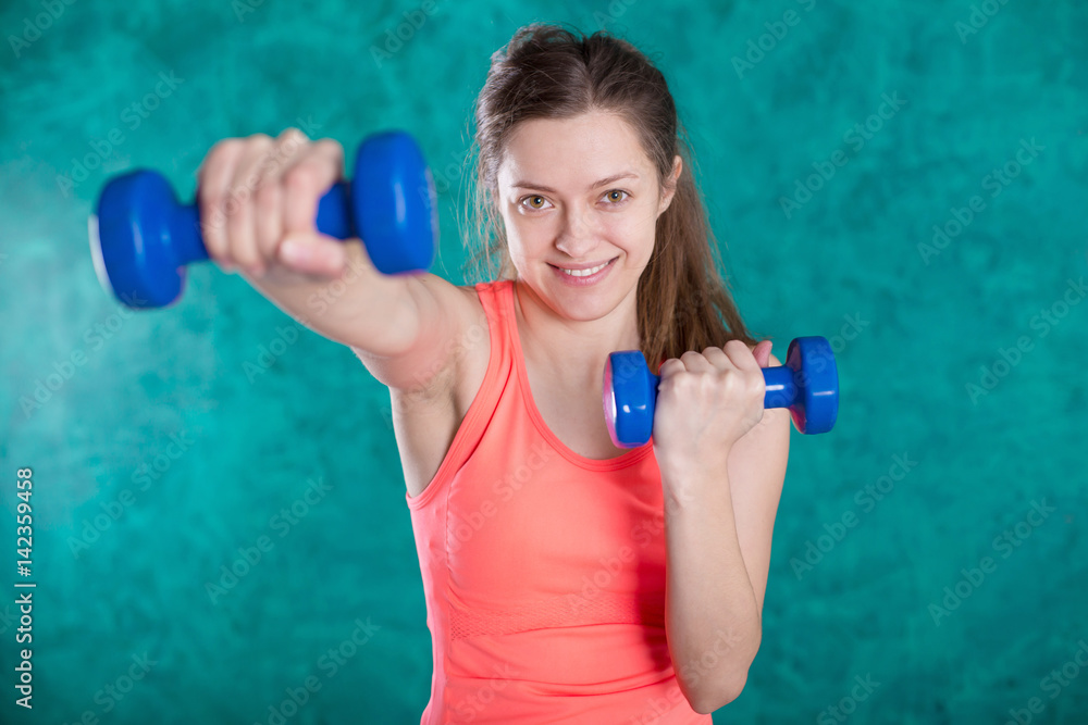 Sport fitness girl with dumbbells - isolated on the turquoise background Sport fitness girl with dumbbells - isolated on the turquoise background