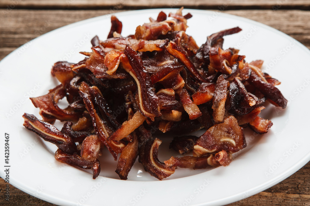 Unhealthy eating habits, junk food. Smoked pig ears served on white plate, close up view. Appetizing beer snack