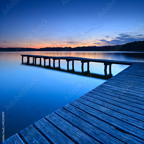 Klarer stiller See bei Sonnenuntergang, Badestelle mit Bootssteg, Mecklenburger Seenplatte photo