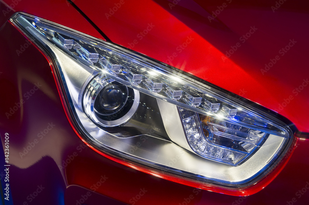 Car headlight with led and xenon lamps of modern sport car with red bodywork 