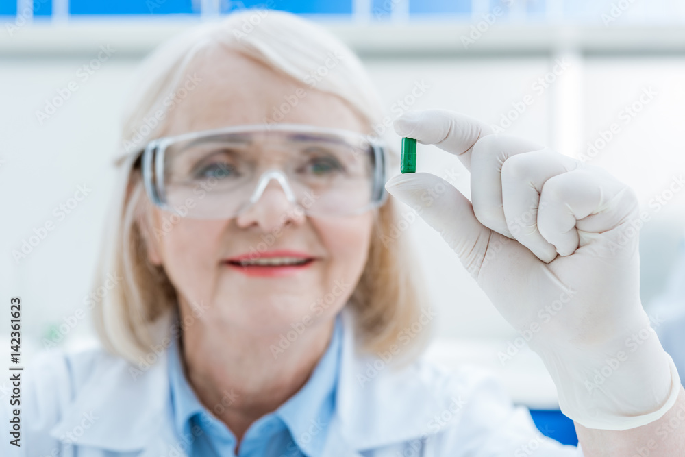 portrait of senior woman scientist analyzing pill in hand in lab portrait of senior woman scientist analyzing pill in hand in lab