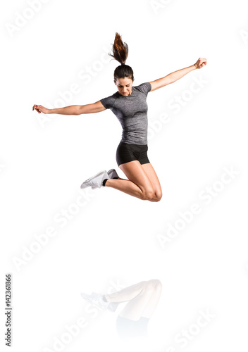 Young fitness woman jumping high. Studio shot, isolated.