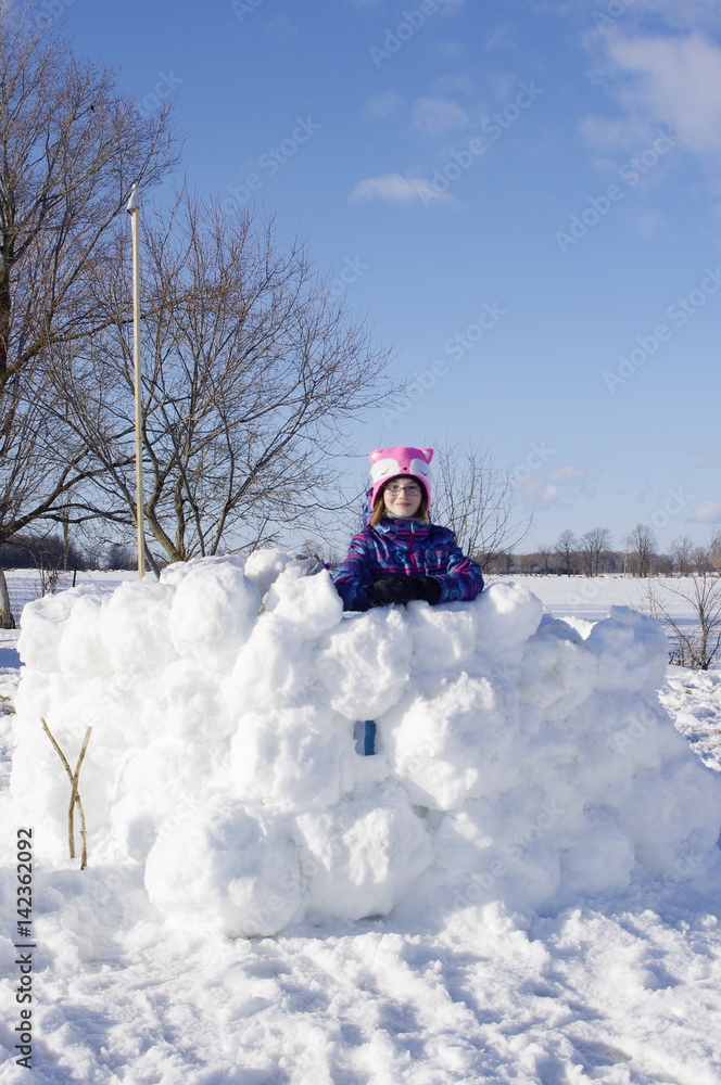 Girl standing in large snow fort