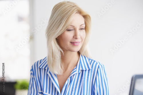 Businesswoman in the office. Portrait of a smiling blond businesswoman doing some paperwork and working on laptop.