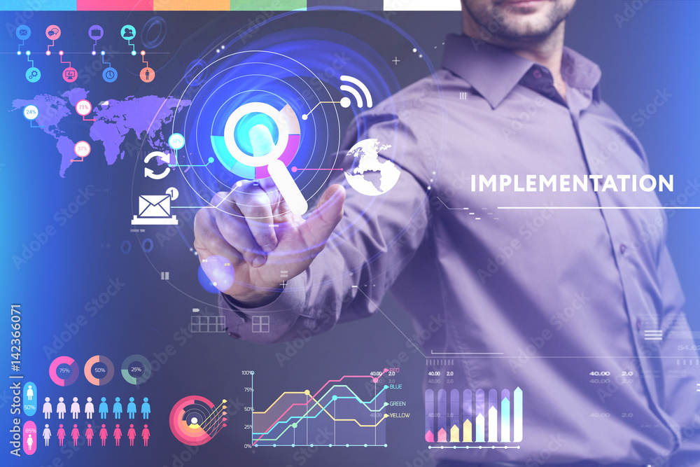 Business, Technology, Internet and network concept. Young businessman working on a virtual screen of the future and sees the inscription: Implementation Business, Technology, Internet and network concept. Young businessman working on a virtual screen of the future and sees the inscription: Implementation