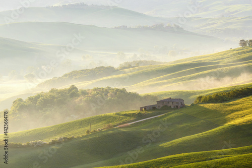 Farm in the valley with fog at sunrise