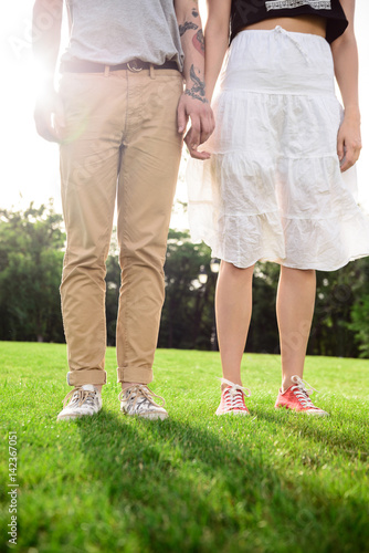 Close up of couple's legs in keds on grass.