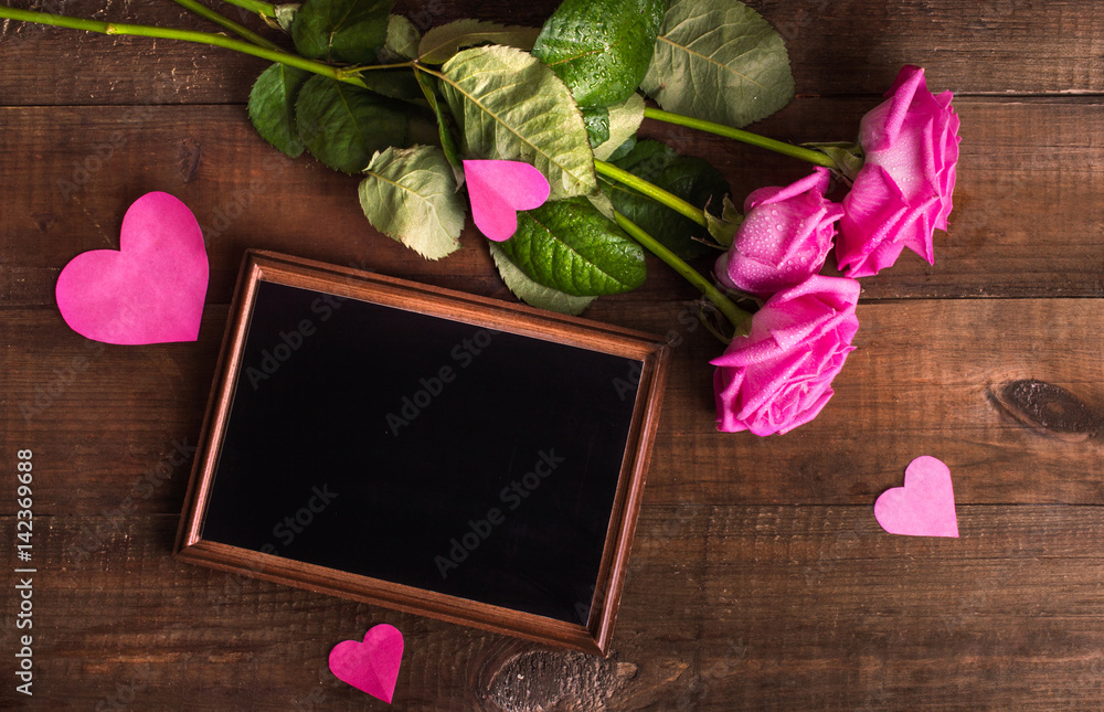 Pink roses and place for text on a wooden background