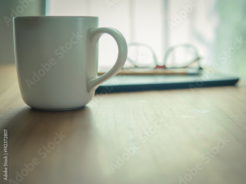 Tablet,glasses,yellow pencil and cup of coffee on wooden table at home office in morning