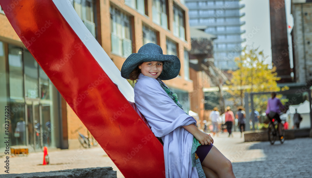 Φωτογραφία Joyful, happy beautiful stylish little girl against city background