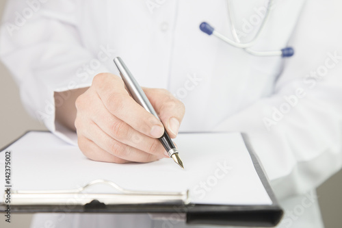 Close-up view of female doctor hands filling patient registration form. Healthcare and medical concept 