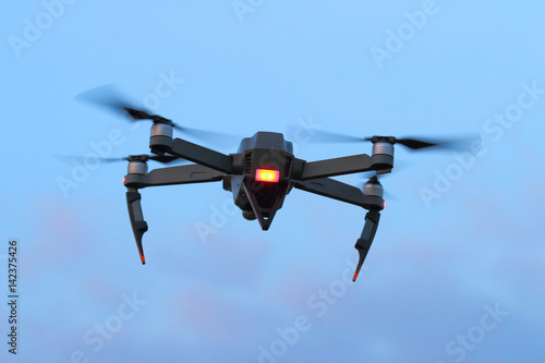 A black spying drone on the evening sky. Crime and terrorism theme.
