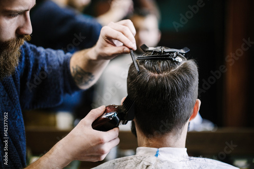Barber cuts man's hair with clipper and brush