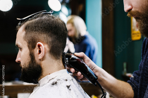 Barber cuts man's hair attentively