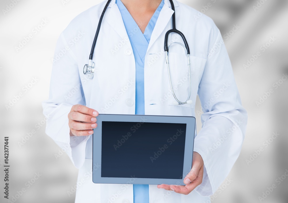 Doctor mid section with tablet against blurry background Doctor mid section with tablet against blurry background