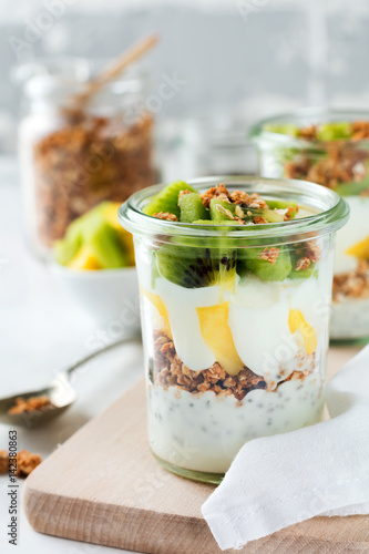 Yogurt granola parfait with mango,kiwi, tropical fruits аnd сhia seeds, layered dessert or breakfast. Selective focus.