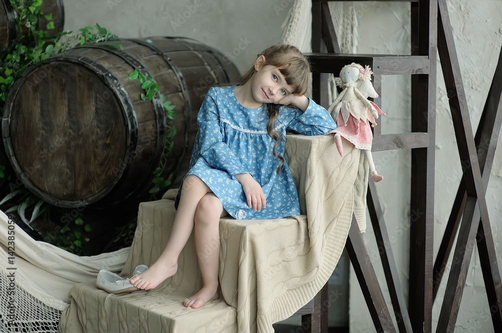 little girl in blue dress sits on a wooden ladder with a rag doll and ...