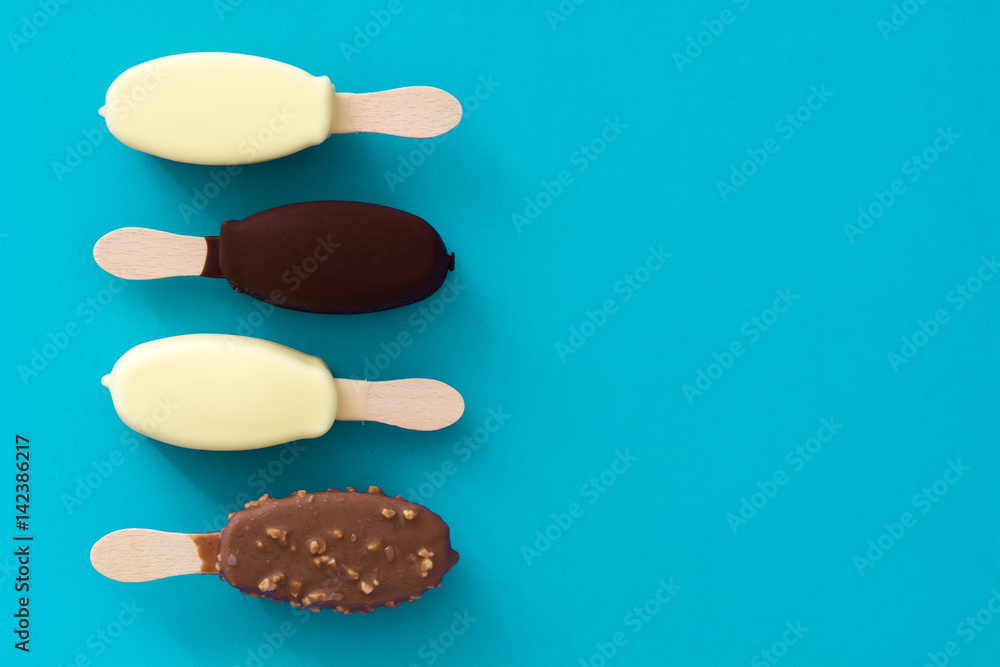 Black and white chocolate ice cream popsicles on blue background.
Black and white chocolate ice cream popsicles on blue background.