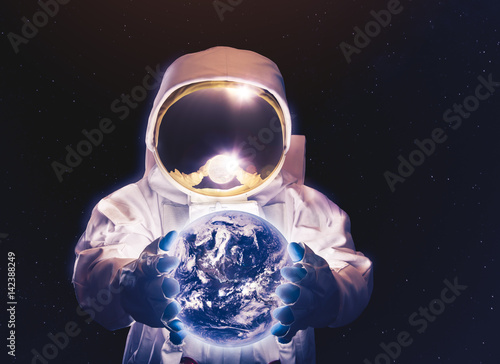 Fototapeta Naklejka Na Ścianę i Meble -  Astronaut in space holding the earth on his hands (Elements of this image were furnished by NASA)