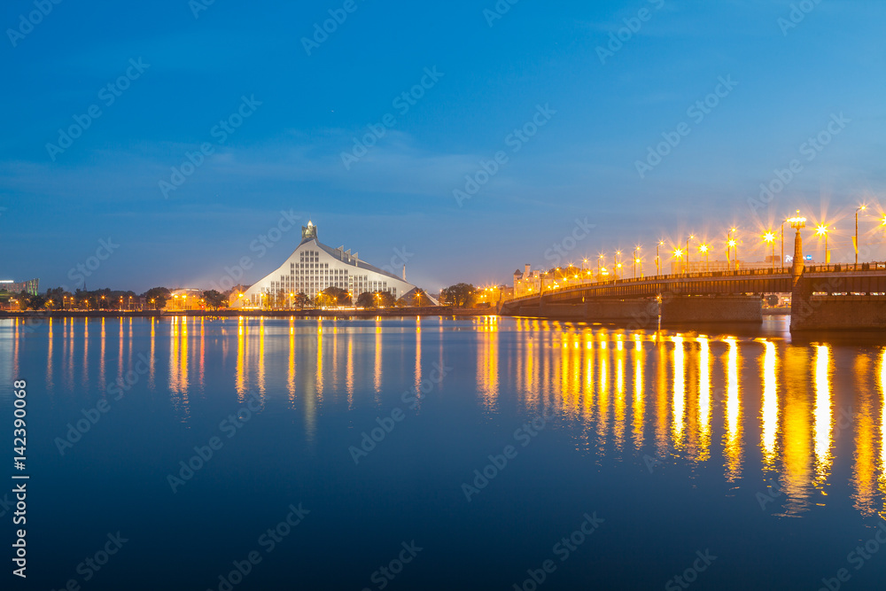 Latvian national library and stone bridge over Daugava river in Riga. Night illuminated scene.