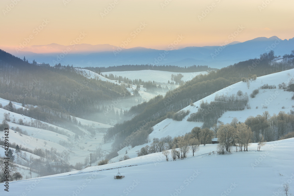 Beautiful winter mountain landscape with snowflakes in frosty winter day. Carpathian wild mountains. Romania. Holbav. Bran. Brasov. Romania. Little noise. Colorful winter sky. Beautiful winter mountain landscape with snowflakes in frosty winter day. Carpathian wild mountains. Romania. Holbav. Bran. Brasov. Romania. Little noise. Colorful winter sky.