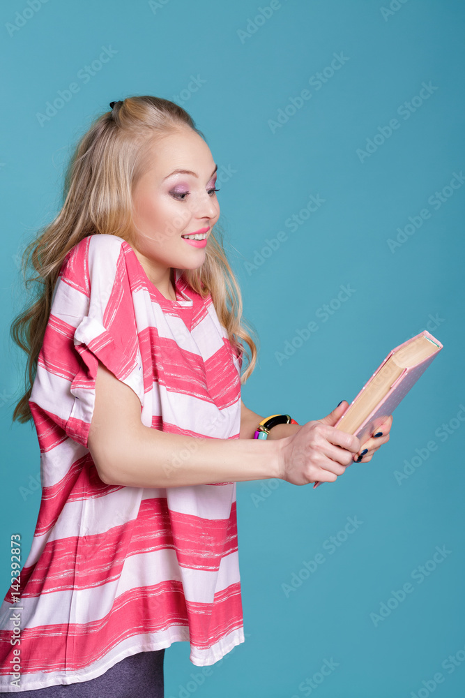 young attractive blond woman holding pink book on blue background young attractive blond woman holding pink book on blue background
