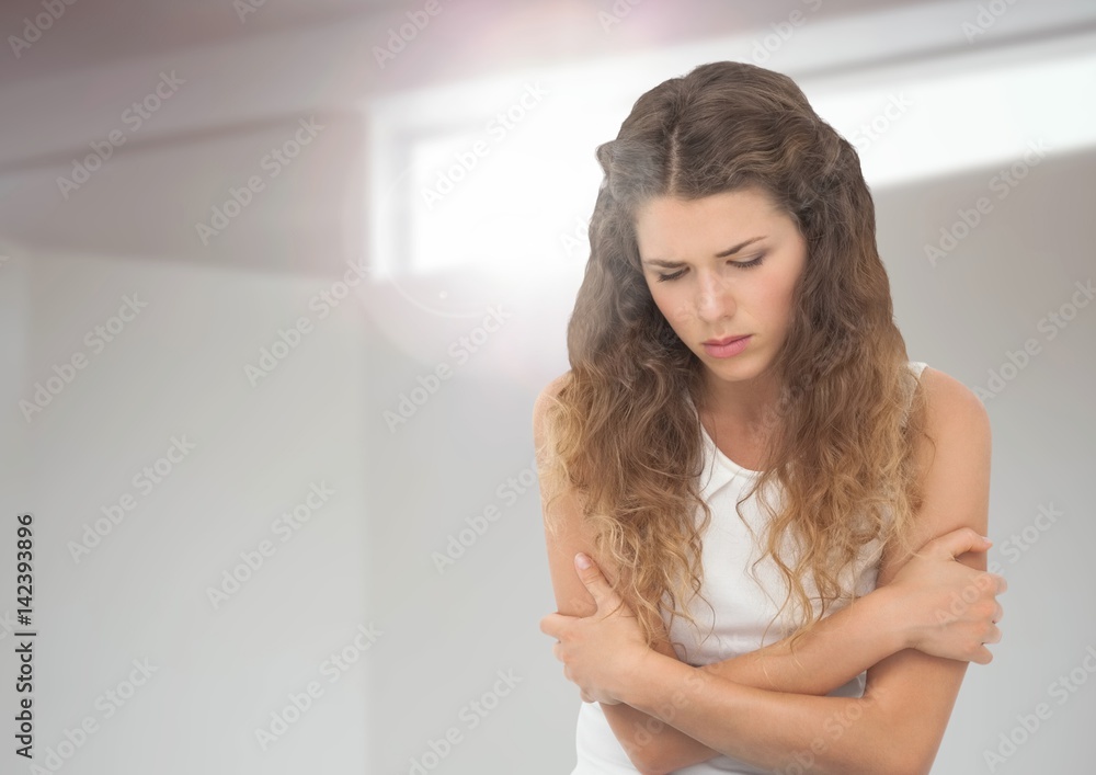 Sad young woman holding herself against window light Sad young woman holding herself against window light