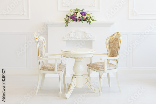 Bright luxury white interior living room with flowers . the walls are decorated with baroque ornaments
