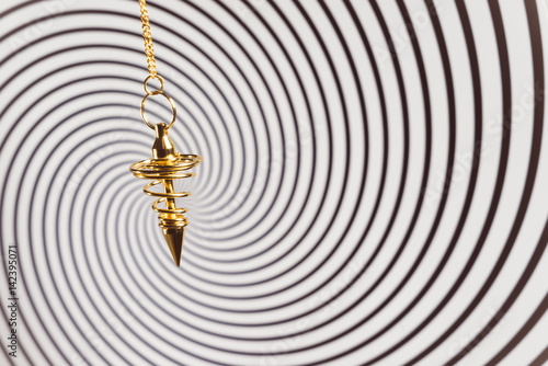 Pendulum used for readings and hypnotism on swirl background photo