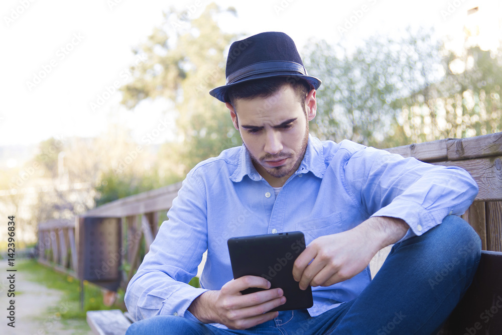 young man modern hipster with the tablet or ebook outdoors young man modern hipster with the tablet or ebook outdoors