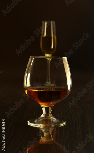 Two glasses of brandy or cognac and bottle on black background
