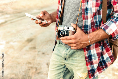 Man holding vintage photo camera and using mobile phone photo