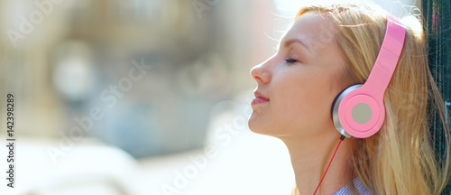 Young woman listening music in headphones in the city