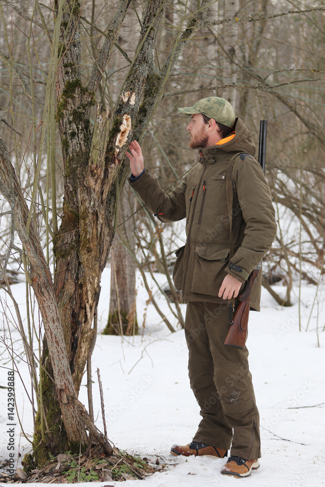 Hunter man with shotgun dressed in dark khaki clothing in the forest Hunter man with shotgun dressed in dark khaki clothing in the forest